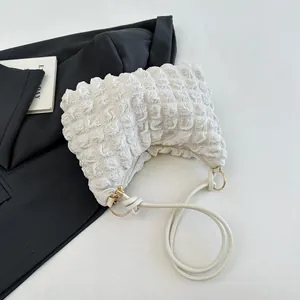 Vue détaillée de la texture plissée du sac nuage crème et de sa boucle en métal doré