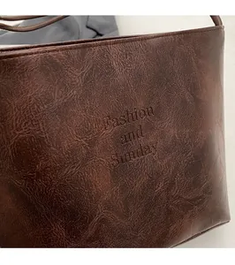 Detail of dark brown suede bucket bag with Fashion and Sunday embossed lettering