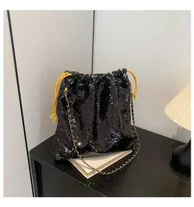 Detail of sequin bucket bag featuring black sparkles and bright yellow drawstring cord