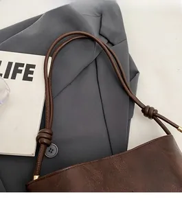 Detail of the brown textured leather bag featuring a fashion stamp and knotted shoulder strap