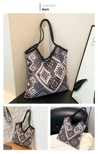 Vista dettagliata della borsa tote nera intrecciata con motivi etnici colorati e manici