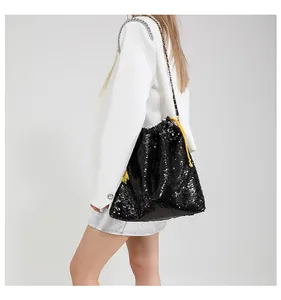Detailed view of black sequin bucket bag featuring yellow drawstring and silver chain strap