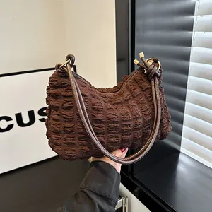 Sac à bandoulière marron foncé plissé en forme de demi-lune avec anneaux dorés
