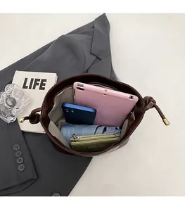 Spacious interior of a dark brown suede bucket bag with tablet and daily essentials