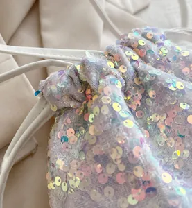 Detailed macro view showing sparkling iridescent sequins and white drawstring on bucket bag