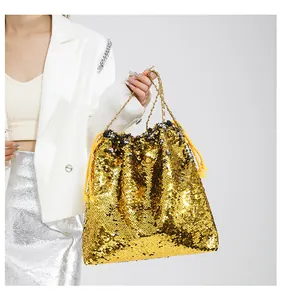 Detail of gold sequined bucket bag with drawstring closure and fine metal chain handle