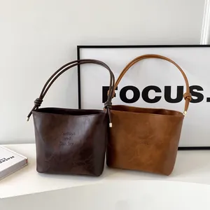 Minimalist faux suede bucket bag with side knot detail and embossed text in two colors