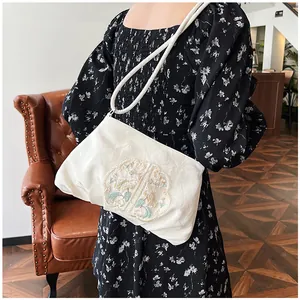 Dettaglio del ricamo floreale e del manico rotondo su borsa hobo in raso bianco