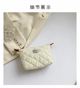 Dettaglio ravvicinato della pochette trapuntata beige con ricamo a rombi alla moda