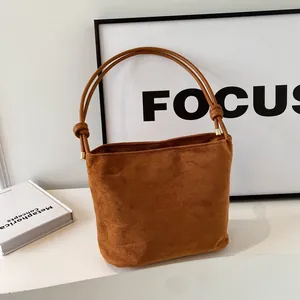 Minimalist caramel suede bucket bag with handcrafted knotted strap and gold hardware accents