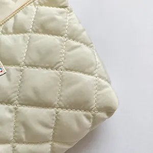 Dettaglio della borsa a busta trapuntata beige con motivo a rombi e cuciture rifinite