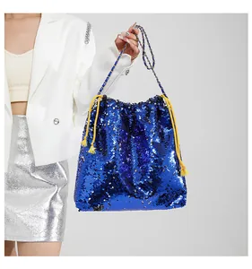Detail of dark blue sequin bucket bag with gold chain strap and yellow tassel drawstring