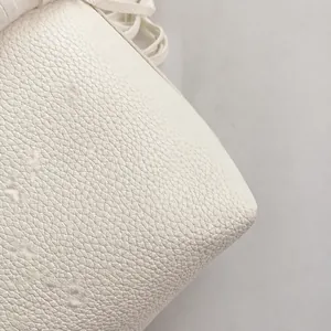 Detailed macro view of white lychee-patterned faux leather texture and clean stitching