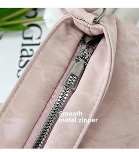 Dettaglio della cerniera in argento lucido su una borsa a tracolla rosa effetto marmo