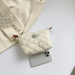 Pochette a busta trapuntata beige con ricamo a rombi e dettaglio della cerniera laterale