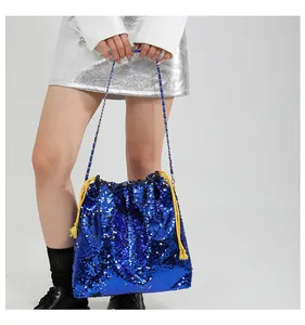 Detail of blue sequin bucket bag featuring a gold drawstring and woven chain strap