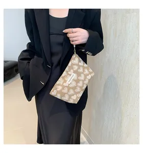 Detailansicht der Canvas-Handtasche mit Herzprint, Perlenarmband und Modeetikett vorne