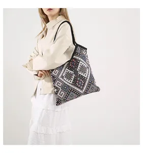 Dettaglio di una borsa tote a righe con motivi etnici colorati su una modella