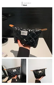 Detalle del bolso de mano acolchado negro con bordado de rombos y adornos de cuero