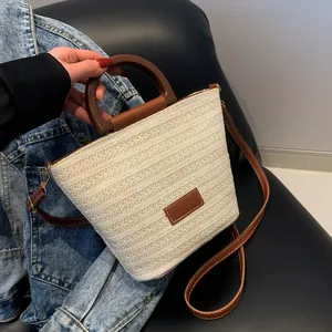 Sac seau tissé en paille blanc crème avec poignées en cuir marron et bandoulière