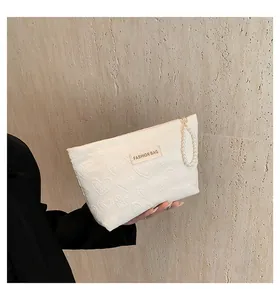 Detailansicht der weißen Canvas-Tasche mit Herzprägung und elegantem Perlen-Handgriff
