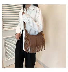 Borsa a tracolla bohémien marrone con frange indossata da una modella con camicia bianca