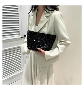 Detail of elegant black sequin clutch bag held by a model in a white blazer