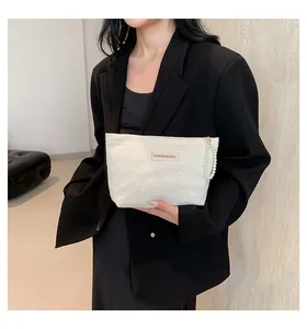 Detail der weißen gesteppten Handtasche mit Herzprägung und elegantem Perlenband