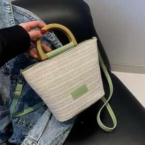 Sac seau en paille tissée avec bordure en cuir vert et poignée en bois tendance