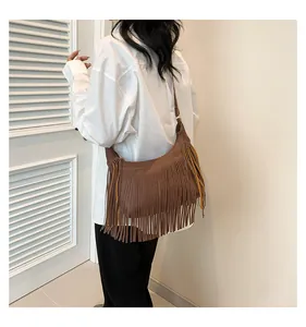 Dettaglio borsa bohémien marrone con frange e pelle litchi indossata da una modella