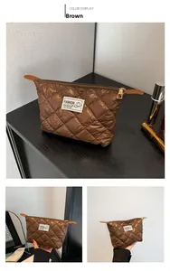 Detalle del neceser de nailon acolchado marrón con bordado de moda y cremallera dorada