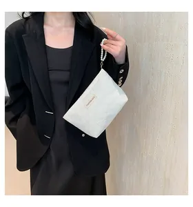Detail der weißen Handtasche mit Herz-Textur und Perlenhenkel zum schwarzen Blazer