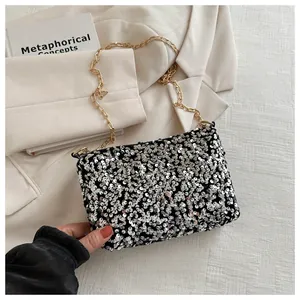Detail der silbernen Pailletten-Beuteltasche mit goldener Kette auf beigem Blazer