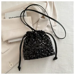 Detail of a sparkly black sequin drawstring bucket bag for women with leather strap