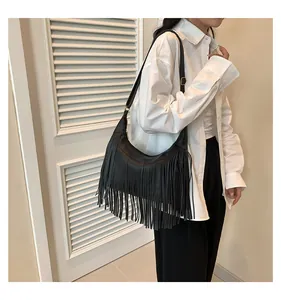 Dettaglio borsa Hobo nera con frange, nappe e finiture dorate indossata da modella