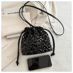 Close-up of black sequin drawstring bucket bag with shiny texture and leather strap