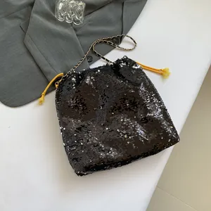 Chic black sequin bucket bag with gold chain strap and yellow tassel drawstring details