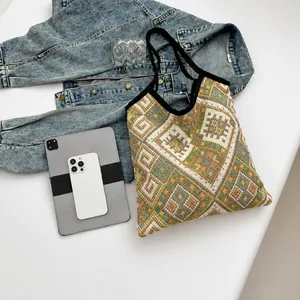 Dettaglio borsa shopper in maglia geometrica con tablet e accessori quotidiani