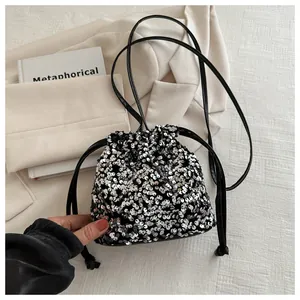 Detail of silver and black sequin bucket bag with drawstring closure and slim strap