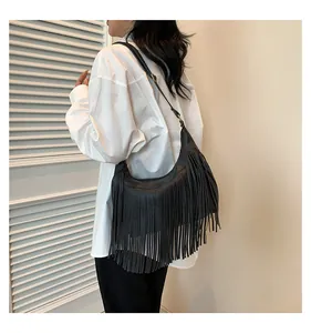 Dettaglio della borsa a sella nera in similpelle scamosciata con lunghe frange e texture cuoio