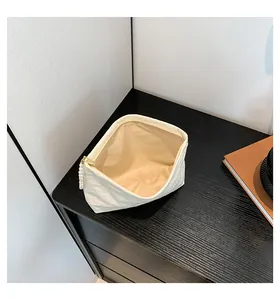 Detailansicht der cremefarbenen Make-up-Tasche mit Herzprägung, Perlenreißverschluss und Goldteilen