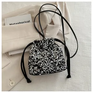Detail of silver sequin bucket bag with drawstring closure on beige fabric background