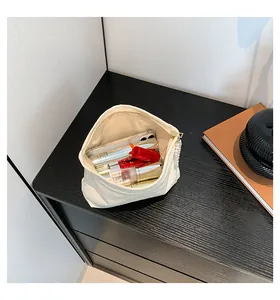 Detailansicht der cremeweißen Kosmetiktasche aus geprägtem Stoff mit großem Fassungsvermögen