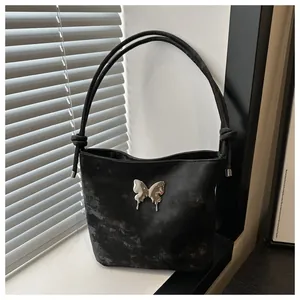 Detalle de mariposa plateada en bolso tipo cubo negro con textura de mármol