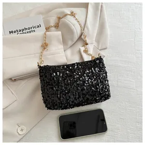 Schicke schwarze Pailletten-Beuteltasche mit Goldkette auf beigem Blazer-Hintergrund