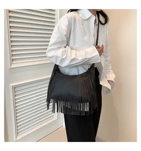 Dettaglio borsa a tracolla nera con frange e texture a grana di litchi su modella