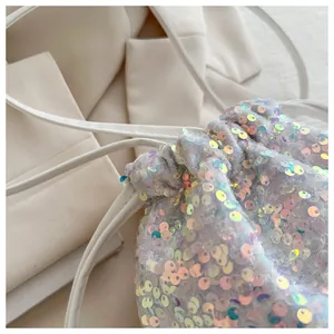 Detail of iridescent sequins and drawstring closure on a white stylish bucket bag