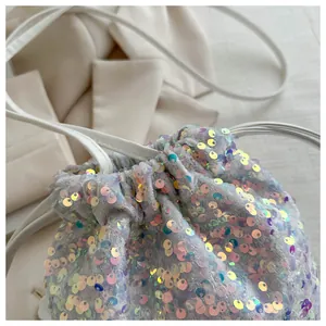 Detailed view of shimmering sequins and white leather drawstring on bucket bag