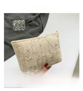 Detailed close-up of beige woven clutch featuring elegant pink and green floral embroidery