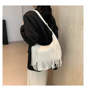 Dettaglio delle lunghe frange bianche su una borsa a tracolla boho in finta pelle scamosciata